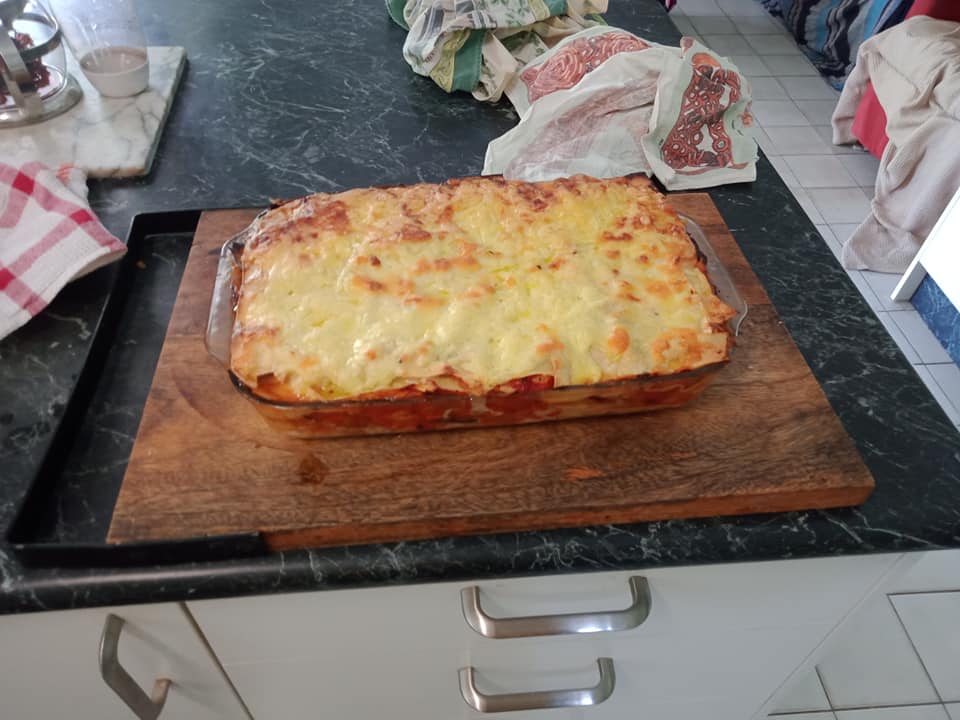 Image of a see-through glass tray containing some lasagne.